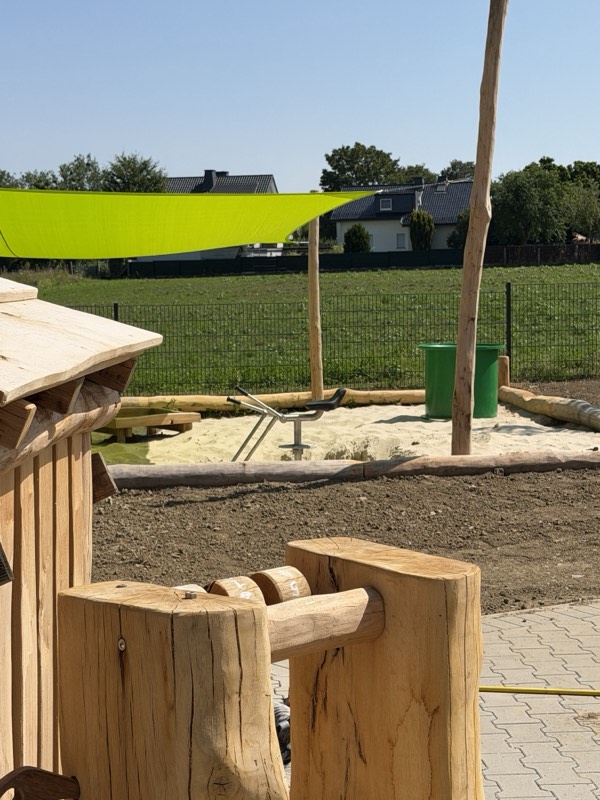Neu angelegter Sandspielbereich mit Sonnensegel im Außengelände der Kita